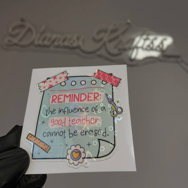Sticker with motivational quote about a good teacher held by a gloved hand.