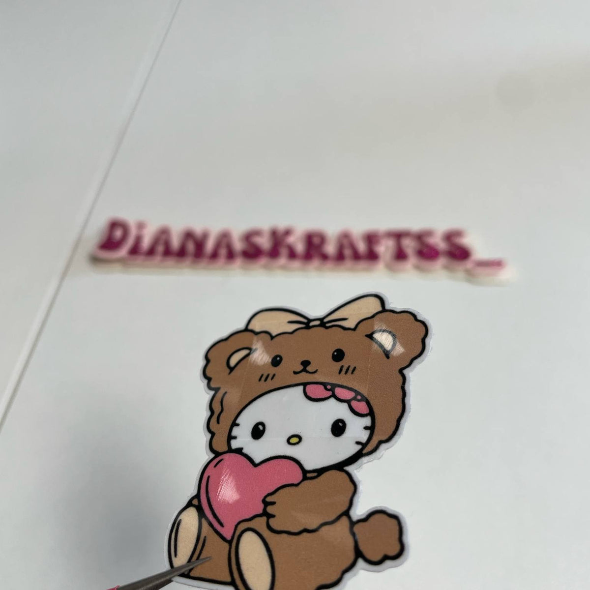 Cartoon bear with a heart and 'DIANASKRAITSS' text on a white background